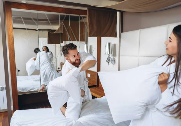 Fröhliches Paar hat Spaß im Schlafzimmer und kämpft zu Hause mit großen Kissen — Stockfoto