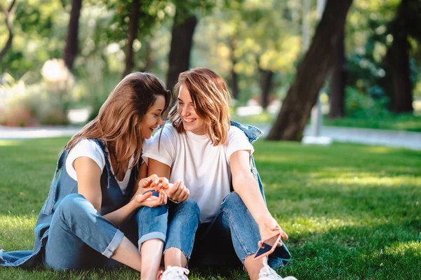 Amigos sinceros sentados en el parque hablando entre sí. —  Fotos de Stock