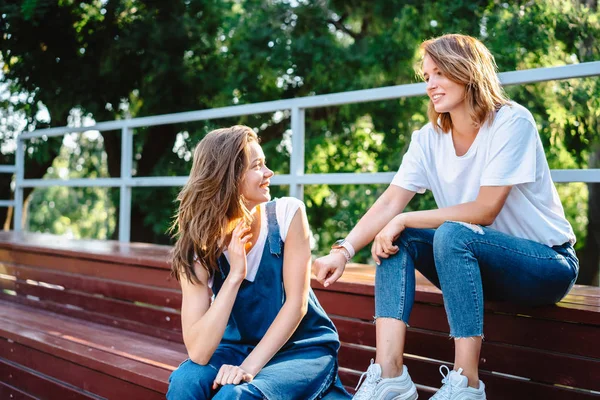 Dos hermosas jóvenes descansando en un banco — Foto de Stock