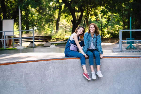 Dwie szczęśliwe młode dziewczyny siedzące w skate parku — Zdjęcie stockowe