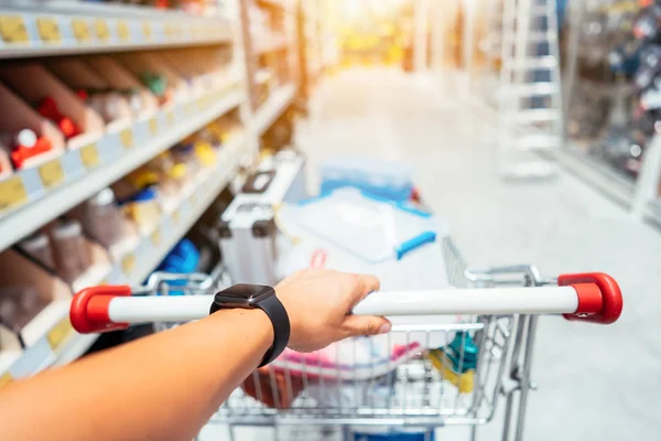 Menschliche Hand hautnah mit Einkaufswagen im Supermarkt — Stockfoto