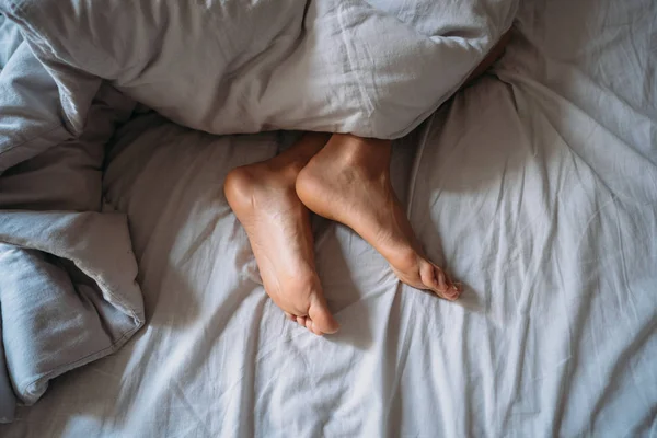 Nahaufnahme Frauenfüße allein im weißen Bett — Stockfoto
