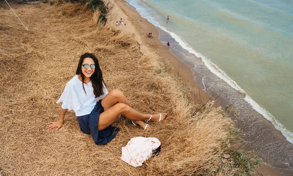 Yazlık etekli ve gömlekli çekici bir kadın sahilde oturuyor. — Stok fotoğraf