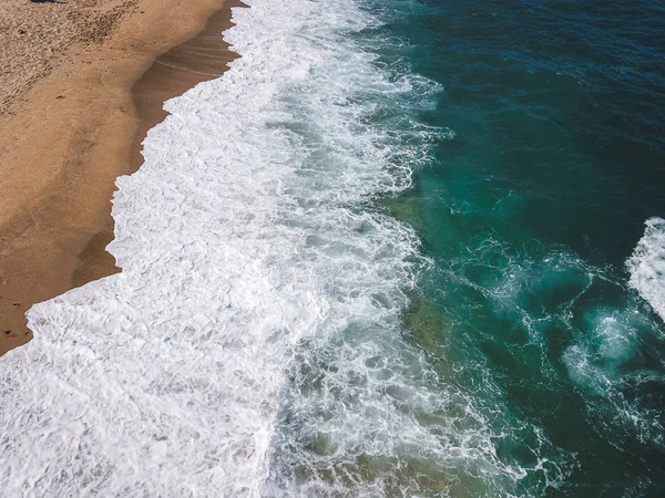 Вид с воздуха на океанские волны, купающиеся на побережье — стоковое фото