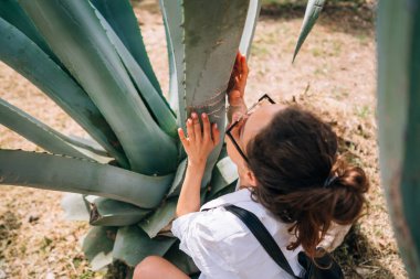 Büyük aloe vera yaprakları poz mutlu güzel kızın arkadan görünüm