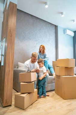 Genç mutlu aile ile çocuk/açma kutuları birlikte kanepede oturan