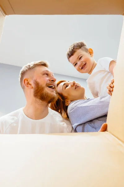 La familia feliz acaba de mudarse a una casa nueva y mirando la caja — Foto de Stock