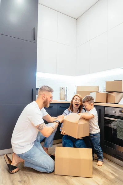 Joven familia desempacando cajas en nuevo hogar — Foto de Stock