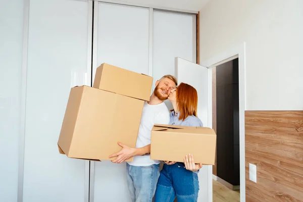Happy couple holding cardboard boxes and moving to new place — Stock Photo, Image