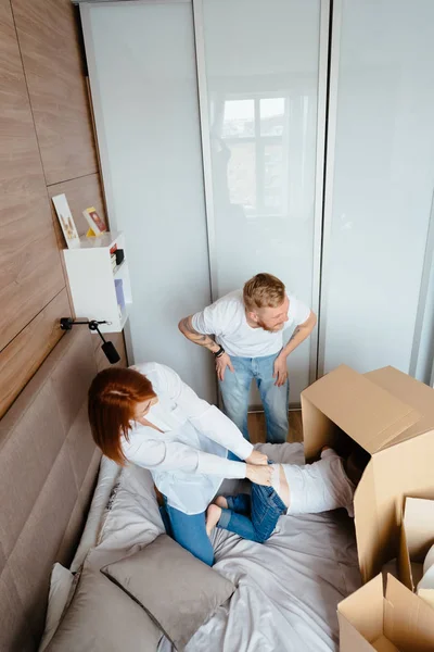 Papá mamá e hijo pequeño juegan en el dormitorio con cajas de papel — Foto de Stock