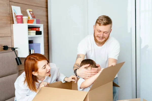 Papá mamá e hijo pequeño juegan en el dormitorio con cajas de papel — Foto de Stock