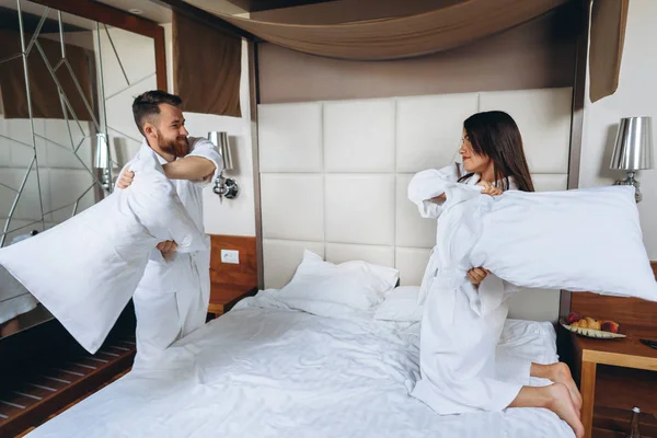 Fröhliches Paar hat Spaß im Schlafzimmer und kämpft zu Hause mit großen Kissen — Stockfoto