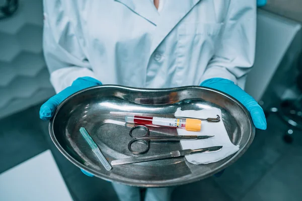 Enfermeira em luvas de borracha segurando uma bandeja de equipamentos médicos cirúrgicos — Fotografia de Stock