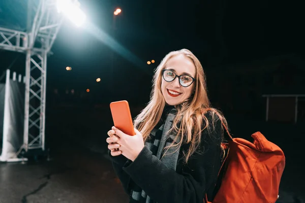 Блондинка со смартфоном ночью на улице . — стоковое фото