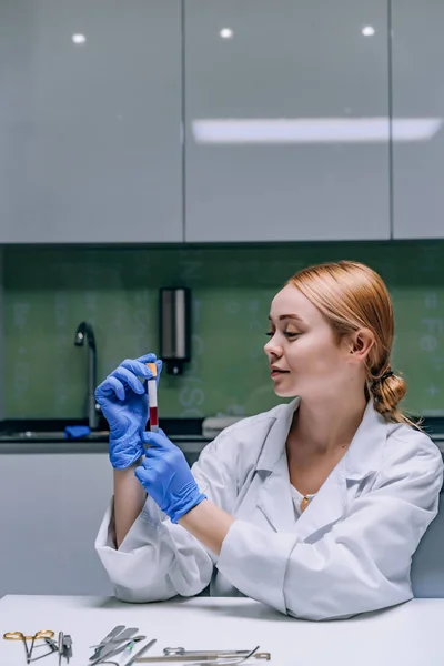 Женщина-медицинский или научный исследователь смотрит на пробирку в лаборатории . — стоковое фото
