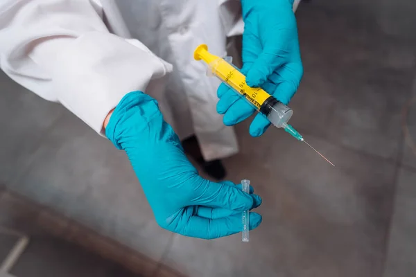 Mãos em luvas de borracha segurar uma seringa médica descartável com o medicamento — Fotografia de Stock