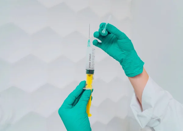 Handen in rubberen handschoenen houden een wegwerp medische injectiespuit met het medicijn — Stockfoto