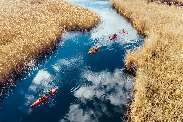 Group of people in kayaks among reeds on the autumn river. — Stock Photo, Image