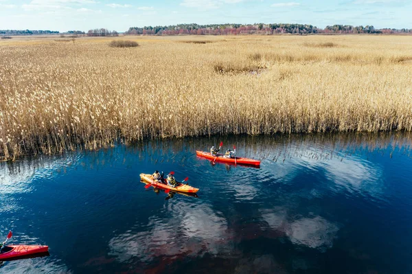 Group of people in kayaks among reeds on the autumn river. — Stock Photo, Image