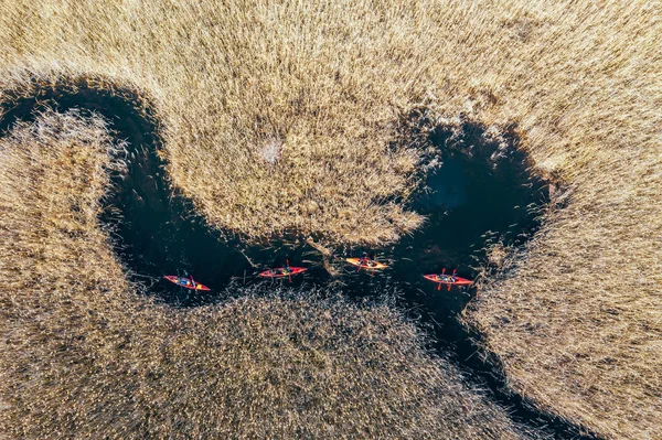 Group of people in kayaks among reeds on the autumn river. — Stock Photo, Image