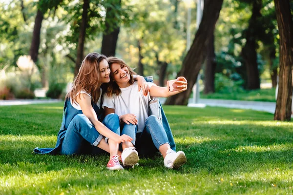 Twee vrouwelijke vriend zit in het park hebben een rust nemen van een selfie — Stockfoto