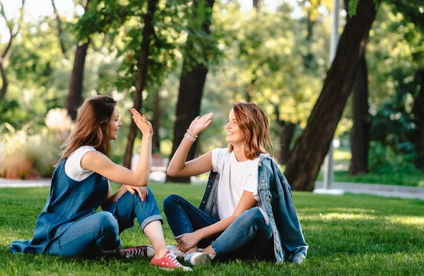 Feliz amigos do sexo feminino levantando as mãos dando alta cinco no parque da cidade — Fotografia de Stock