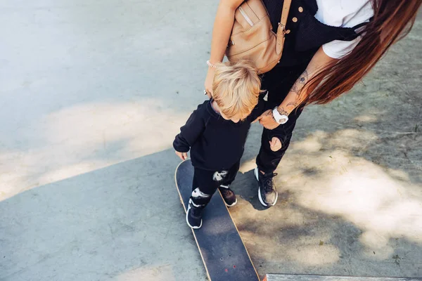 Mladá matka učí svého malého chlapce jezdit na skateboardu — Stock fotografie