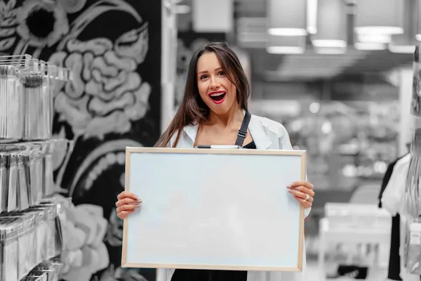 Usmívající se bruneta žena drží bílou prázdnou desku — Stock fotografie