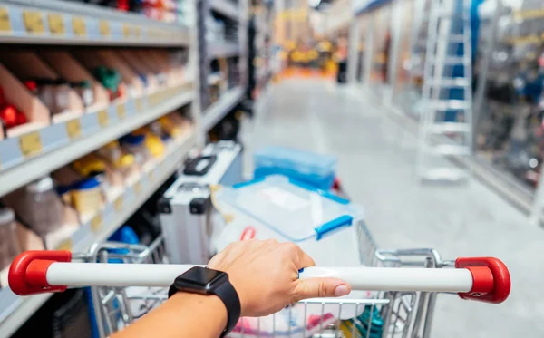 Menschliche Hand hautnah mit Einkaufswagen im Supermarkt — Stockfoto