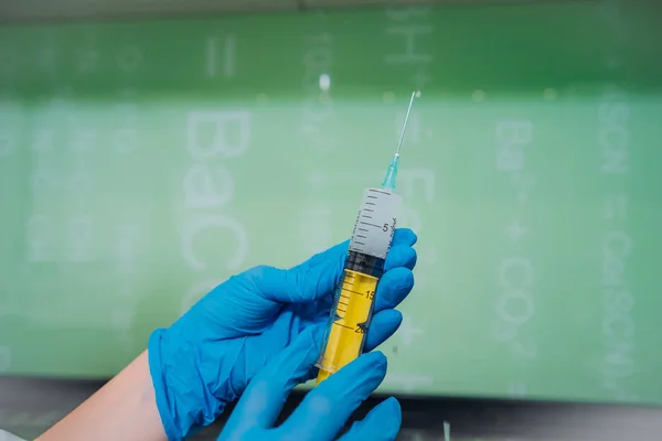 Mãos em luvas de borracha segurar uma seringa médica descartável com o medicamento — Fotografia de Stock