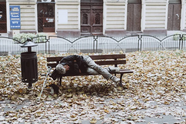 Sem-teto dormindo nos bancos no parque de outono — Fotografia de Stock