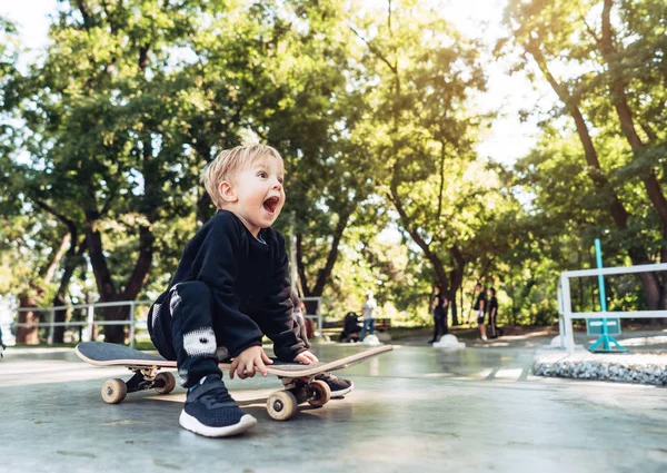 Jeune enfant assis dans le parc sur une planche à roulettes . — Photo