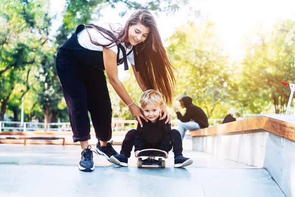 Giovane madre insegna il suo bambino a cavalcare uno skateboard — Foto Stock