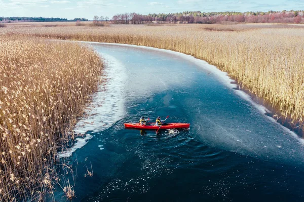 两个运动的人漂浮在河里的一条红色小船上 — 图库照片