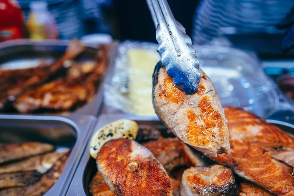 Filete de salmón cocido al horno en la parrilla en tong de cocina . — Foto de Stock