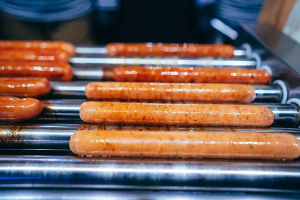 Przygotowanie francuskiego Hot Dog. Spinning kiełbasy na grillu — Zdjęcie stockowe