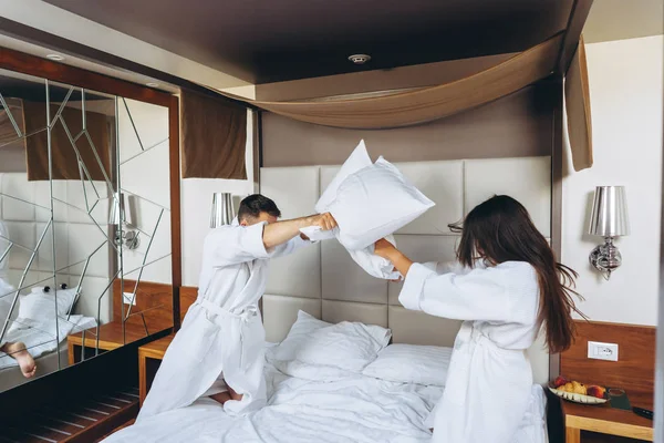 Весела пара розважається в спальні, бореться з великими подушками вдома — стокове фото