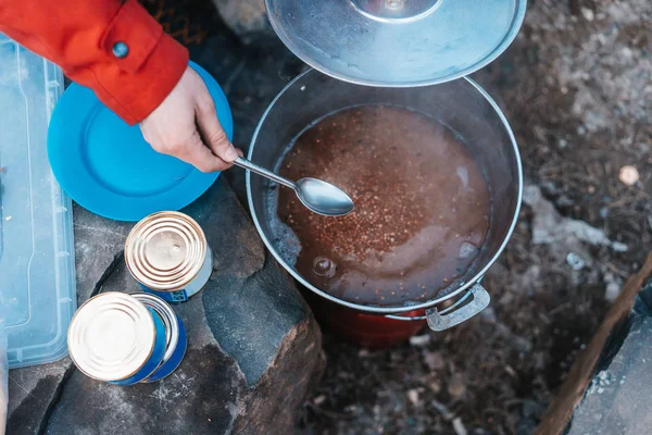 Camper preparing meal in large kettle on campfire — Stock Photo, Image