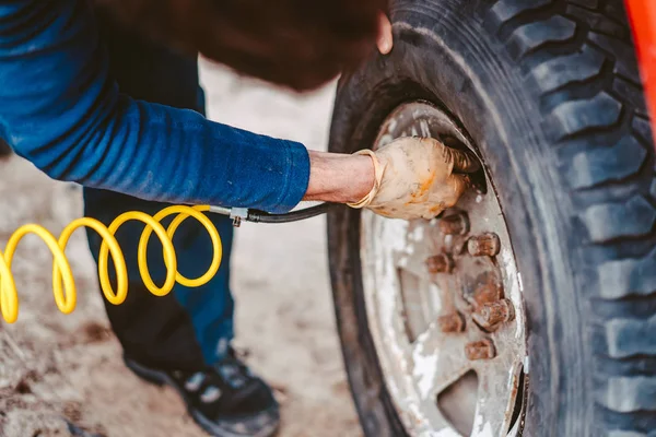 A man pumps air wheel with a compressor — Stock Photo, Image