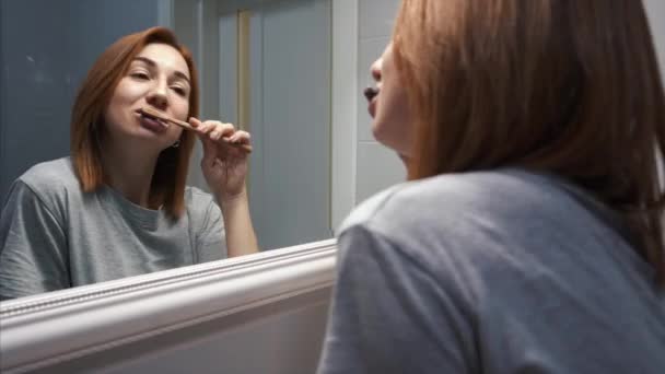 Ładna młoda kobieta w łazience szczotkowanie zębów — Wideo stockowe
