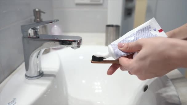 Mulher apertar tubo e colocar pasta de dentes na escova . — Vídeo de Stock