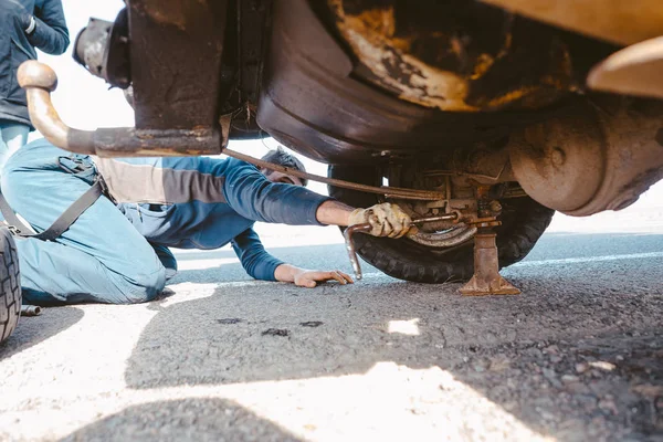 Adam toprak yolda 4x4 bir arabanın altında yatıyor. — Stok fotoğraf