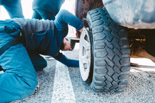 El hombre cambia la rueda manualmente en un camión todoterreno 4x4 — Foto de Stock