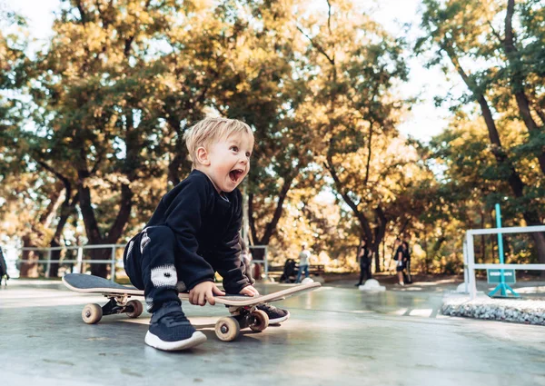 Jeune enfant assis dans le parc sur une planche à roulettes . — Photo