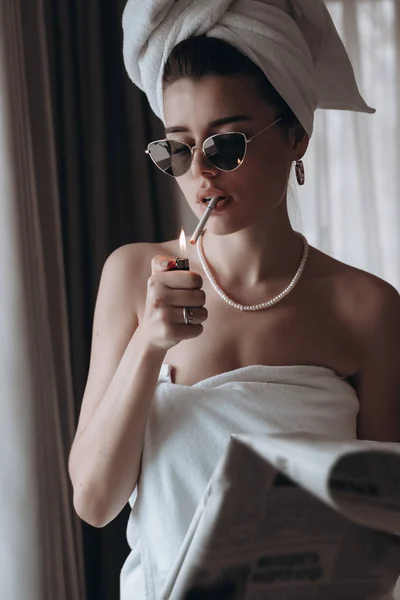 Belle jeune femme dans une serviette fume une cigarette et lit le journal — Photo