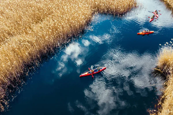Group of people in kayaks among reeds on the autumn river. — Stock Photo, Image