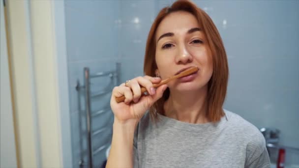 Pretty young woman in the bathroom brushing her teeth — Stock Video