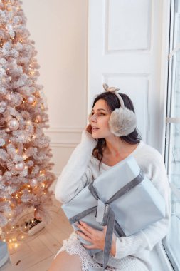 Noel ağacının yanında zarif elbiseli genç bir kadın.