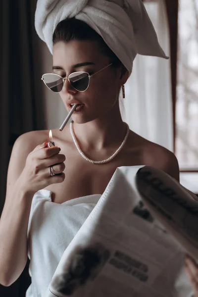 Belle jeune femme dans une serviette fume une cigarette et lit le journal — Photo