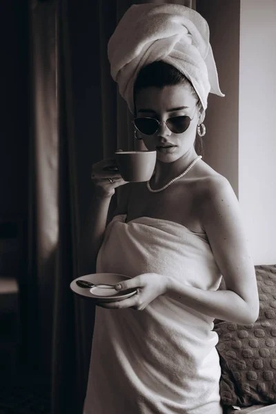 Menina envolto em uma toalha depois de um chuveiro beber café — Fotografia de Stock